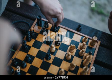 Mains déplaçant des pièces d'échecs sur un échiquier en bois extérieur Banque D'Images