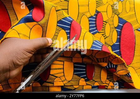 vue de dessus de couper le tissu ankara avec des ciseaux, flatlay de tissu de cire nigérian Banque D'Images