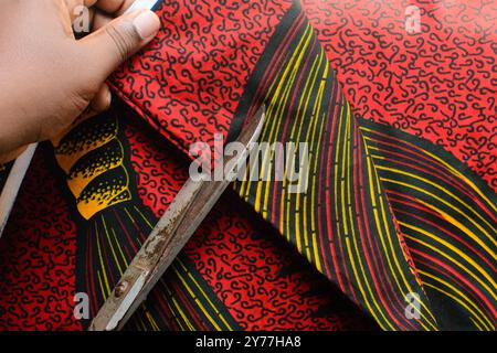 vue de dessus de couper le tissu ankara avec des ciseaux, flatlay de tissu de cire nigérian Banque D'Images