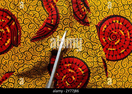 vue de dessus de couper le tissu ankara avec des ciseaux, flatlay de tissu de cire nigérian Banque D'Images