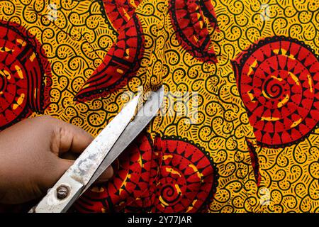 vue de dessus de couper le tissu ankara avec des ciseaux, flatlay de tissu de cire nigérian Banque D'Images