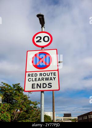 Panneaux de signalisation affichant une indication de dégagement et une limite de vitesse de 20 mi/h sous un ciel nuageux. Banque D'Images