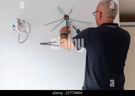 Électricien, examine la connexion du câble dans la ligne électrique. Le technicien tire le fil du conduit sur le chantier. Constructeur au travail, examine conne Banque D'Images