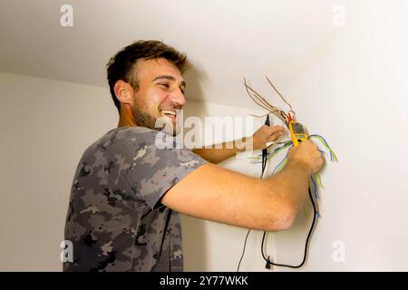 Électricien, examine la connexion du câble dans la ligne électrique. Le technicien tire le fil du conduit sur le chantier. Constructeur au travail, examine conne Banque D'Images