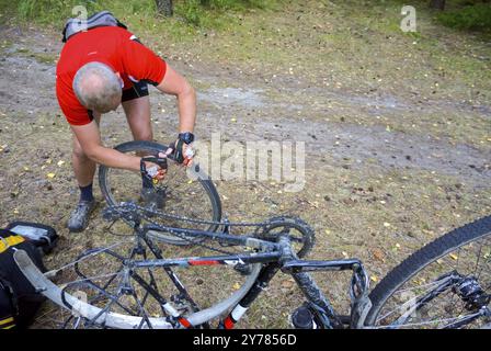 Homme répare roue de vélo, roue de vélo crevée, trou dans pneu de vélo, forêt, région de Kaliningrad, Russie, Europe de l'est, 31 juillet 2019, Europe Banque D'Images