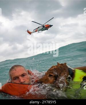 Île de Sanibel, États-Unis. 26 septembre 2024. Un marin et son Golden Retriever sont secourus de leur voilier handicapé par un nageur de sauvetage de la Garde côtière américaine dans le golfe du Mexique lors de l'ouragan de catégorie 3 Helene, le 26 septembre 2024 au large de l'île de Sanibel, en Floride. Le second maître de 2e classe de l'USCG, Todd Hudson, technicien de survie aéronautique à la station aérienne de la Garde côtière de Clearwater, a effectué un sauvetage en eau depuis le bateau qui coule dans des conditions extrêmes et a hissé l'homme et le chien en lieu sûr. Crédit : AST2 Todd Hudson/NOAA/Alamy Live News Banque D'Images