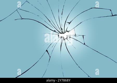 Élément fissuré sur la fenêtre cassée, texture pour le design. Un trou au centre du verre bleu Banque D'Images