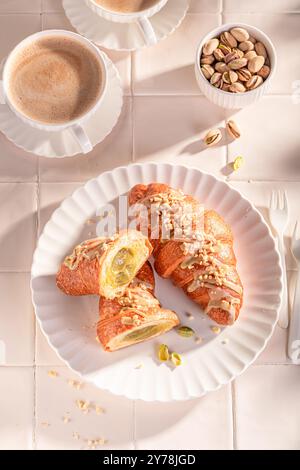 Croissants savoureux et frais à la pistache servis avec du café chaud. Cuisine sucrée française. Banque D'Images