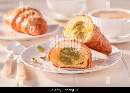 Croissants faits maison et chauds à la pistache servis avec du café chaud. Dessert français sucré. Banque D'Images