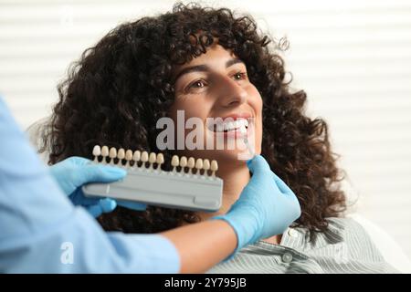 Docteur vérifiant la couleur des dents de la jeune femme en clinique, gros plan. Facettes dentaires Banque D'Images