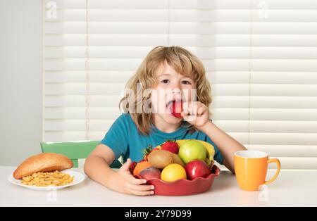 L'enfant mange des fraises, des fruits biologiques. Enfant préadolescent garçon de 7, 8, 9 ans manger des légumes sains. Banque D'Images