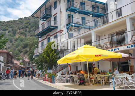 Pedoulas, Chypre - 11 juin 2023 : touristes appréciant la journée ensoleillée de marche par restaurant local et hôtel avec balcons dans la rue entourée de Troodos mou Banque D'Images