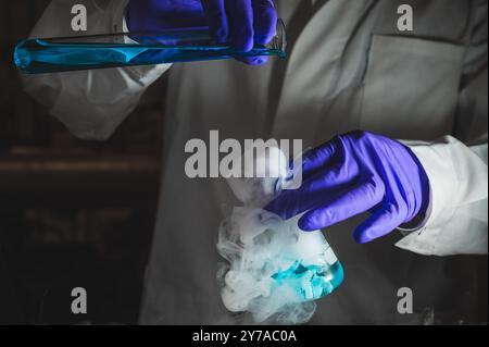 Une femme scientifique effectuant une réaction organique dans des conditions fumantes dans un laboratoire. Fumées, radioactives, fluorescence. Un arrière-plan noir d'espace de copie. Banque D'Images