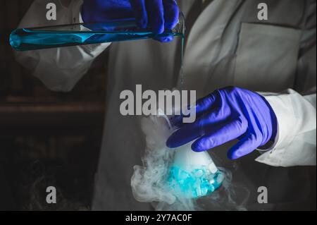 Une femme scientifique effectuant une réaction organique dans des conditions fumantes dans un laboratoire. Fumées, radioactives, fluorescence. Un arrière-plan noir d'espace de copie. Banque D'Images