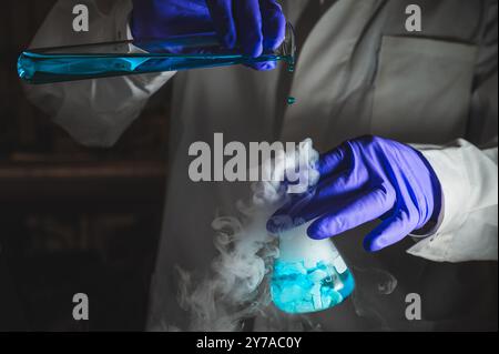 Une femme scientifique effectuant une réaction organique dans des conditions fumantes dans un laboratoire. Fumées, radioactives, fluorescence. Un arrière-plan noir d'espace de copie. Banque D'Images