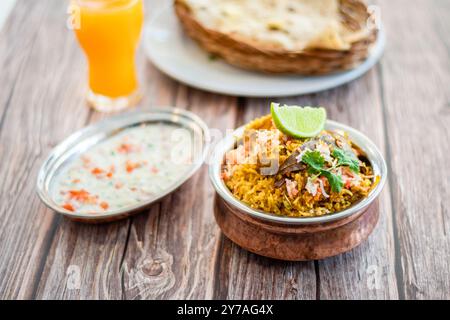 Épicé biryani pulao indien dans un bol doré avec plat de riz basmati Inde avec curry de viande de poulet Ramadan Kareem, Eid. Bol de service en laiton avec dos blanc Banque D'Images