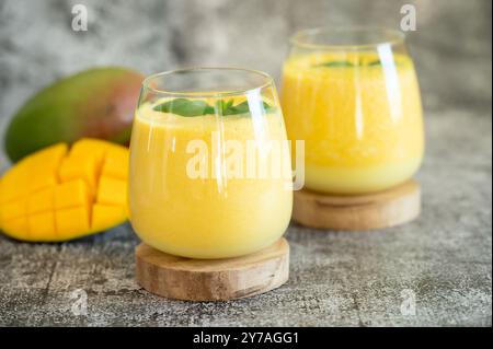 Lassi à la mangue fraîche dans des verres sur fond gris avec espace de copie. Boisson froide ayurvédique indienne saine detoxic avec mangue. Lassi fraîcheur en yogur Banque D'Images