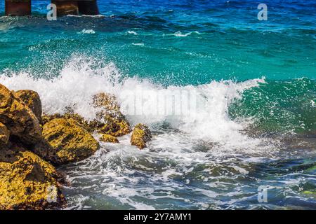 Les vagues de la mer des Caraïbes s'écrasent contre la rive rocheuse avec des éclaboussures et de l'eau turquoise sur l'île de Curaçao. Banque D'Images