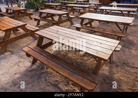 Tables de pique-nique en bois placées sur un sol sablonneux, mises en place dans un restaurant extérieur pour dîner ou se détendre à la plage sur l'île de Curaçao. Banque D'Images