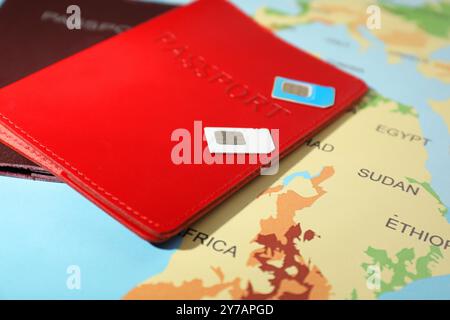 Cartes SIM modernes et passeports sur la carte du monde, gros plan Banque D'Images