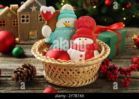 Délicieux biscuits en forme de bonhommes de neige et décor de Noël sur table en bois Banque D'Images