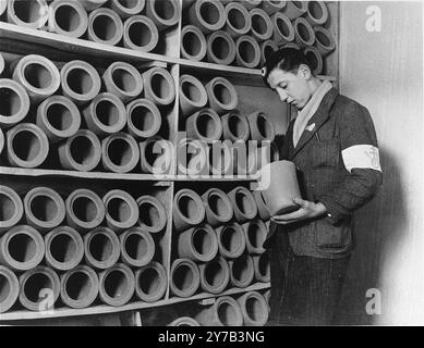 Un membre de la résistance française examine les urnes utilisées pour enterrer les restes incinérés des prisonniers à Natzweiler-Struthof. Ce camp, en Alsace, était le seul camp nazi sur le sol français. C'était un camp de travail, un camp de transit et, au fur et à mesure de la guerre, un lieu d'exécution. On estime que 22 000 personnes y sont mortes. Banque D'Images