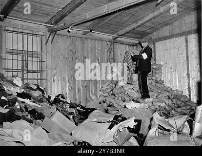 Un membre de la résistance française trie dans un entrepôt rempli de vêtements de prisonniers jetés dans le camp de concentration de Natzweiler-Struthof. Ce camp, en Alsace, était le seul camp nazi sur le sol français. C'était un camp de travail, un camp de transit et, au fur et à mesure de la guerre, un lieu d'exécution. On estime que 22 000 personnes y sont mortes. Banque D'Images