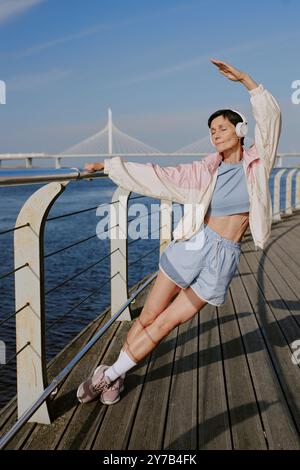 Plan vertical d'une femme détendue étirant tout le corps sur le front de mer Banque D'Images