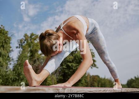 Gros plan moyen d'une athlète qui réchauffe les muscles de son dos et de ses jambes avant l'entraînement principal Banque D'Images