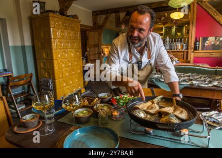 Le chef René Bobzin prépare du poisson désossé avec divers plats de pommes de terre dans la cuisine du Bauernstube de Bobzin et les présente personnellement à la table des convives. Dewichower Straße, Usedom-Süd, Mecklembourg-Poméranie occidentale, Allemagne Banque D'Images