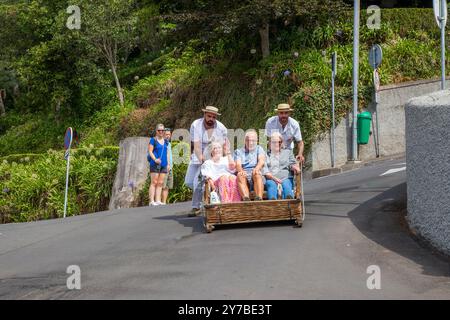 Les vacanciers et les touristes s'amusant en faisant un tour dans les luges traditionnelles en osier à Monte, Funchal sur l'île portugaise de Madère Banque D'Images