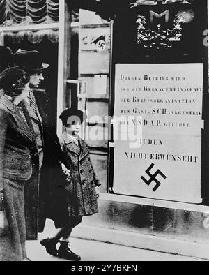 Les piétons viennois voient un grand panneau nazi affiché sur une vitrine de restaurant informant le public que cette entreprise est gérée par une organisation du Parti national-socialiste et que les Juifs ne sont pas les bienvenus. Banque D'Images