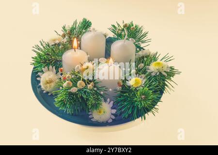 quatre bougies blanches de l'avent, décoration couronne avec fleurs et pin, isolé, deuxième bougie de l'avent allumée Banque D'Images