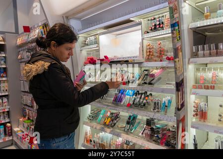 Une femme d'âge moyen choisit des cosmétiques et des produits de maquillage dans un magasin Banque D'Images