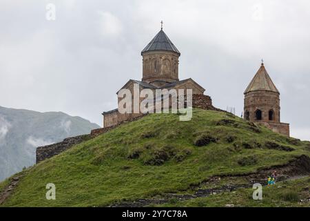 Une vue imprenable sur une chaîne de montagnes avec une ancienne église de la Trinité Gergeti, sous le mont Kazbek près du village de Stepantsminda en Géorgie Banque D'Images