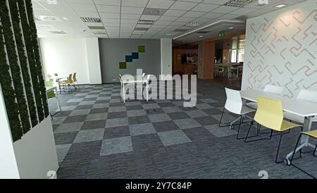Un espace de bureau moderne et minimaliste avec des murs blancs, un sol à damiers et un mobilier élégant. La chambre dispose d'une variété d'options de sièges, y compris Banque D'Images