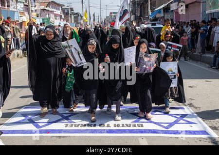 Des femmes et des enfants musulmans du Cachemire marchent sur le drapeau israélien lors d'une manifestation contre le meurtre du chef du Hezbollah Hassan Nasrallah. Des milliers de manifestants sont descendus dans les rues de Srinagar et du Cachemire pour pleurer et condamner l'assassinat du chef du Hezbollah Hassan Nasrallah et d'autres hauts commandants lors d'une frappe aérienne israélienne. Le Hezbollah a confirmé la mort de son chef, Hassan Nasrallah, samedi après que les Forces de défense israéliennes ont frappé ce qu'elles ont appelé le « quartier général central » du Hezbollah avec une grève massive le vendredi 27 septembre 2024, qui a rasé plusieurs bâtiments résidentiels dans l'état de la Terre Banque D'Images