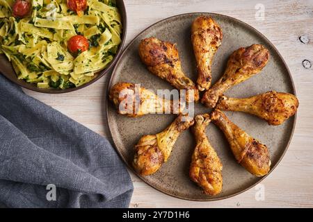 Délicieuse recette thaïlandaise de pilons de poulet épicé grillé, prête à être servie avec penne rigate avec sauce au fromage bleu et épinards Banque D'Images