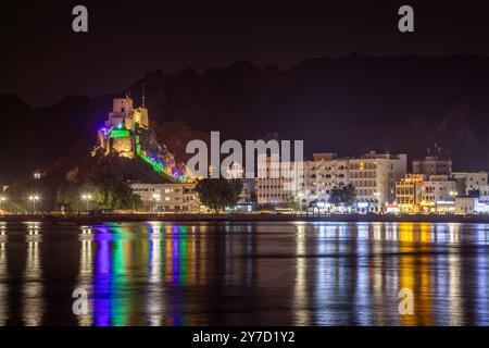 Panorama de promenade de la corniche de nuit avec le château de Mutrah illuminé sur la colline et la baie de la mer mise en évidence, Muscat, sultanat Oman Banque D'Images