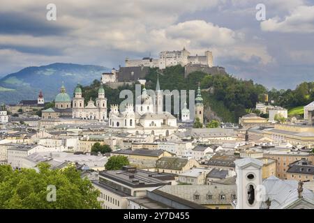 Vue de Salzbourg avec la forteresse Hohensalzburg en arrière-plan et le centre-ville historique au premier plan, entouré de montagnes sous un nuageux Banque D'Images