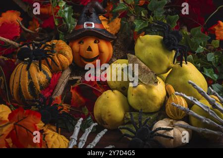La nature morte d'Halloween avec des coings, des citrouilles, des araignées et une citrouille avec un chapeau de sorcière Banque D'Images