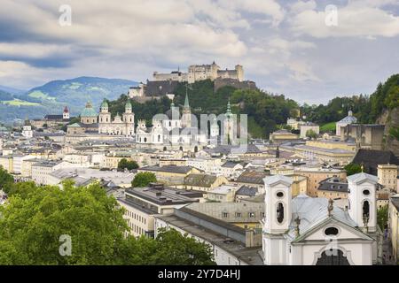 Vue de Salzbourg avec la forteresse Hohensalzburg en arrière-plan et le centre-ville historique au premier plan, entouré de montagnes sous un nuageux Banque D'Images