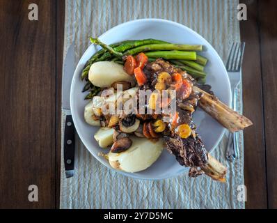 Côtes de bœuf braisées gourmandes aux asperges et aux pommes de terre servies sur un plat blanc Banque D'Images