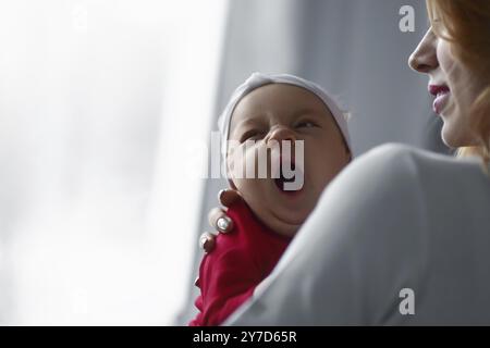 Mère tenant mignonne bébé nouveau-né dans ses bras. Bébé endormi bâillant Banque D'Images