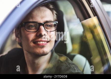 Profitez de la conduite. Image d'un jeune beau gars assis dans la voiture Banque D'Images