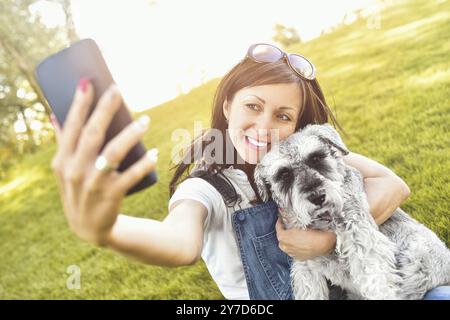 Portrait of a happy woman qui épouse son bien-aimé chien et fait avec lui selfies .Le concept d'amour pour les animaux. meilleurs amis. Race de chien Schna Banque D'Images