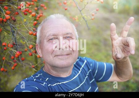 Grand-père retraité positif, fait selfie avec un smartphone dans le parc. un homme âgé marche dans la nature Banque D'Images