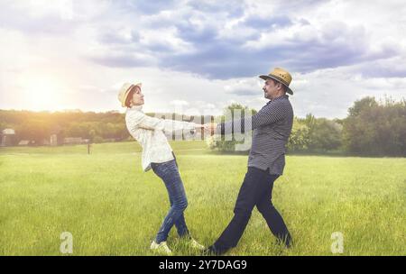 Un portrait d'un couple heureux d'âge moyen tenant la main dans le champ vert Banque D'Images