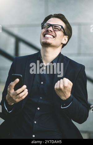 Heureux homme d'affaires caucasien dans des lunettes habillé à l'usure classique debout dans la rue Banque D'Images