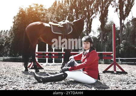 Jeune fille jockey et son cheval posant après l'entraînement. Elle aime les animaux et passe joyeusement son temps dans leur environnement Banque D'Images